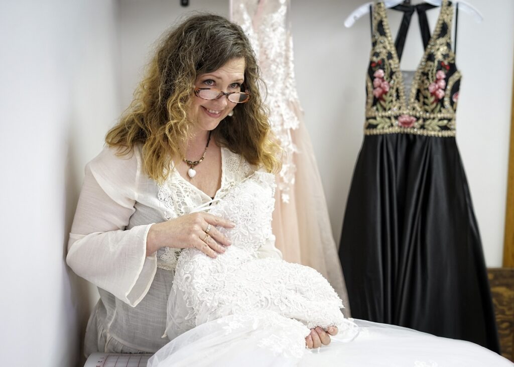 Woman examining lace detail on a wedding dress in a bridal boutique.
